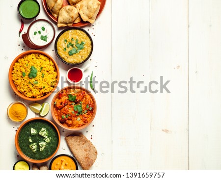 Indian cuisine dishes: tikka masala, dal, paneer, samosa, chapati, chutney, spices. Indian food on white wooden background. Assortment indian pakistani meal with copy space. Top view or flat lay Royalty-Free Stock Photo #1391659757