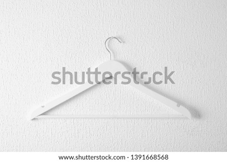 Empty clothes hanger on light wall. Wardrobe accessory