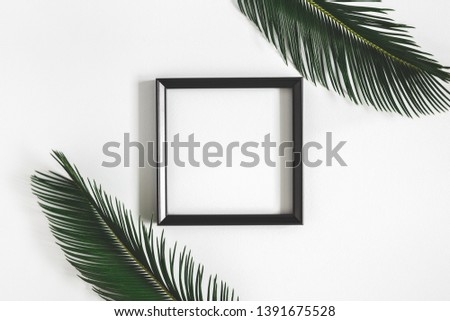 Summer composition. Tropical palm leaves, white photo frame on gray background. Summer, nature concept. Flat lay, top view, copy space