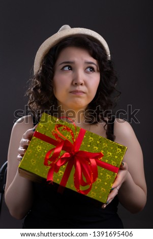 beautiful girl with a gift in her hands looks away on a black background