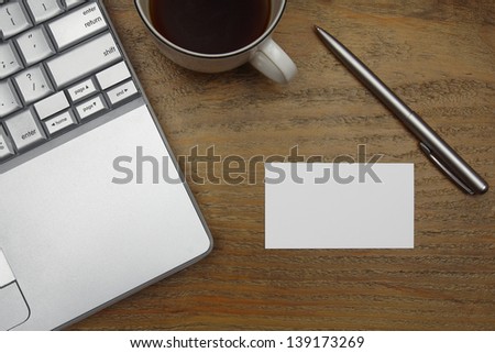 laptop, coffee, business card with pen on old wooden desk