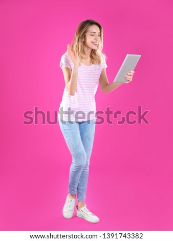 Woman using tablet for video chat on color background