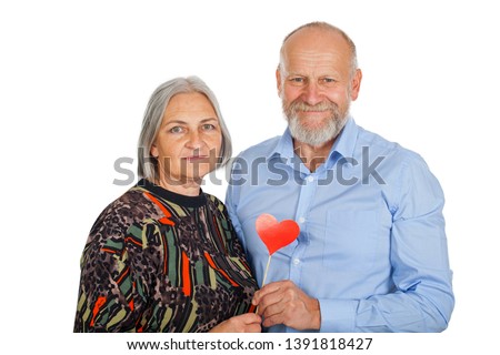 Senior couple holding red heart photo accessory, smiling to the camera on isolated background - romantic concept
