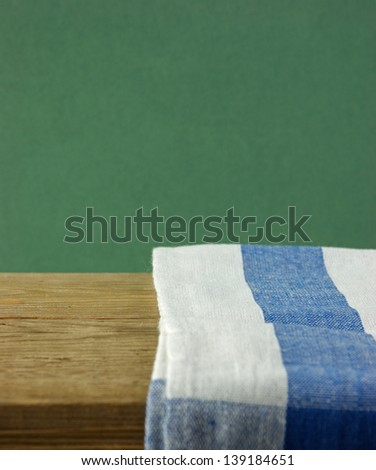 Table-napkin and old wooden deck table with green grunge background
