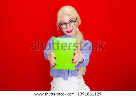 Blondhead female businesswoman smiling in glasses holding notebook, over red background