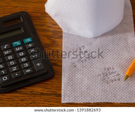 Incorrect calculations on white toilet paper isolated on a wooden surface conceptual image with copy space in landscape format