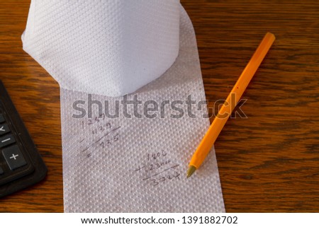 Incorrect calculations on white toilet paper isolated on a wooden surface conceptual image with copy space in landscape format