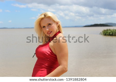 Blond female model at the beach in red swimsuit