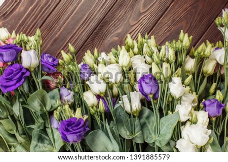 many flowers lying on a brown wooden background angle from above