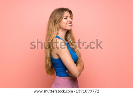 Young blonde woman over isolated pink background in lateral position