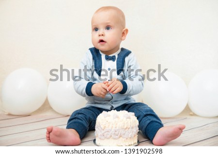 One year baby birthday party. Baby eating birthday cake. Caucasian boy on a light background celebrates.
