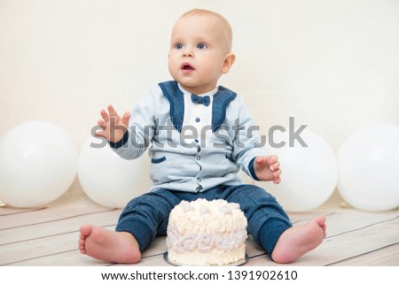 One year baby birthday party. Baby eating birthday cake. The boy on a light background celebrates.