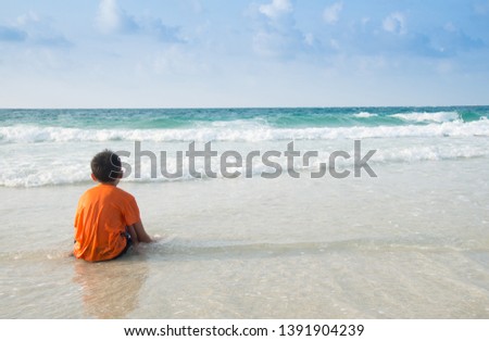 Asian boy living alone at the beach, happy to relax at the sea on holiday, very beautiful beach.Leisure travel concept