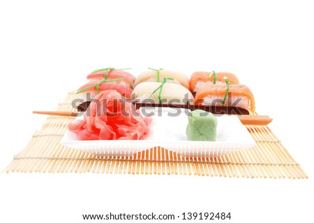 Japanese traditional cuisine - Different Types of Nigiri Sushi : Tuna (maguro) Salmon (sake) and Eel (unagi) with Wasabi and Ginger on bamboo mat isolated over white background