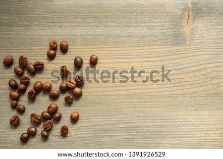 Handfuls of coffee beans scattered on the background of raw wood. A pinch of coffee. Background for text for your coffee house or bakery.
