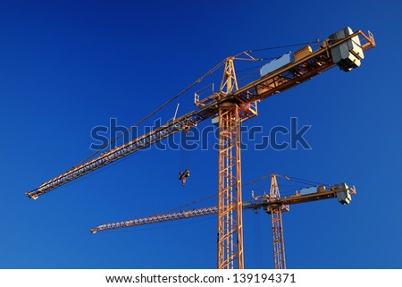 Two tower cranes against blue sky