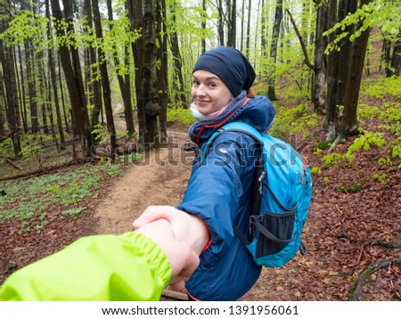 Young happy girl traveler with a smile invites to follow her into the mountains of Bieszczady. The concept of a safe vacation for two.