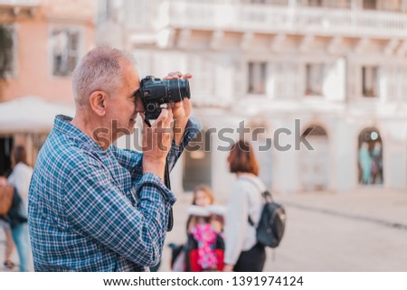 Old senior man on holidays taking pictures with camera, enjoying retirement traveling and sightseeing 