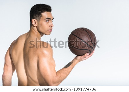 handsome athletic mixed race man with muscular torso holding brown ball on white