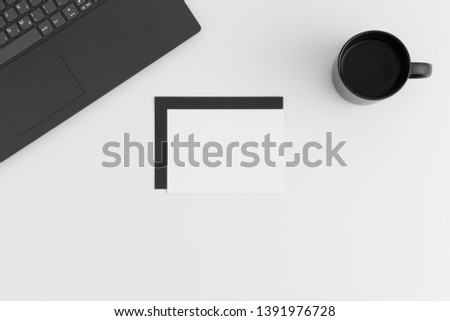 Top view of a white card mockup and envelope with a laptop and a cup of coffee on a white table.