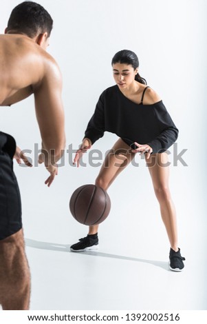 attractive african american girl in black leotard playing ball with mixed race man on white