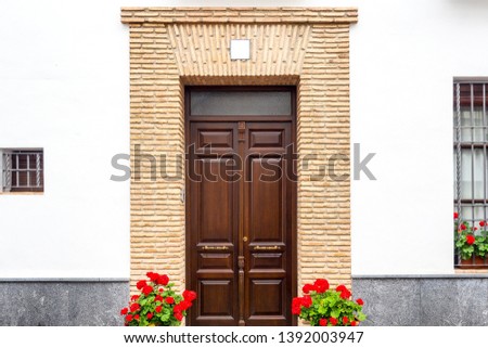 The beautiful exterior facade with a classic wooden door and flower pots