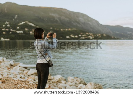 Beautiful young female tourist on holidays enjoying and taking photos with mobile phone