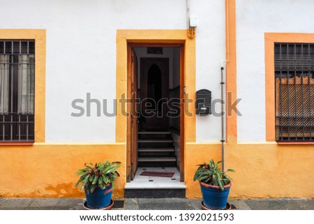 The colorful exterior facade with a wooden door and yellow frame