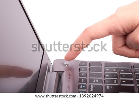 Close-up view of female hand with index finger, pushing start button of silver laptop with black keyboard and display. Turns the notebook on or off. Isolated on white background. Royalty-Free Stock Photo #1392024974