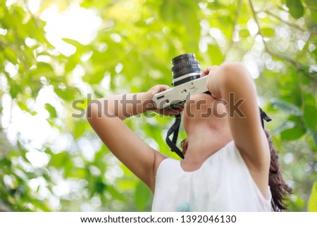 Child girl holding camera and taking photo in garden
