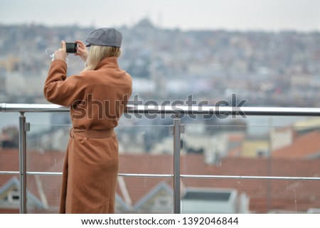 blonde girl taking picture of landscape