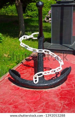 Black ship anchor with white chain on red background