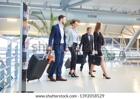 Business people as a business team with luggage on business trip in airport terminal Royalty-Free Stock Photo #1392058529