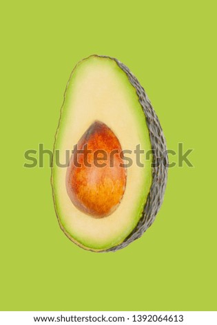 Half avocado levitate in air on green pastel background. Concept of vegetable levitation.