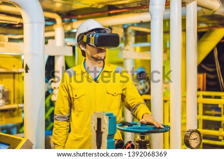 Young woman in a yellow work uniform, glasses and helmet uses virtual reality glasses in industrial environment, oil Platform or liquefied gas plant