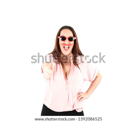 Pretty young woman doing a thumb up gesture with her hand while wearing red sunglasses against a white background