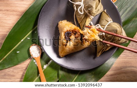 Zongzi, woman eating steamed rice dumplings on wooden table, food in dragon boat festival duanwu concept, close up, copy space, top view, flat lay Royalty-Free Stock Photo #1392096437