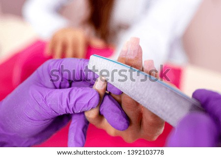 Rounding the shape of a nail with nail file, manicure treatment