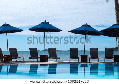 Summer beach resort with chair and umbrella reflection in the pool.