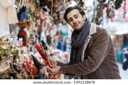 Smiling man choosing decorations at Christmas market outdoor