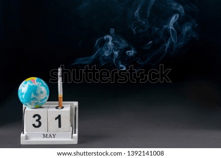 World no tobacco day, Healthcare and medical concept.  Closeup cigarette, Wooden Block calendar with globe on  black background.Using for advertiser or  background.