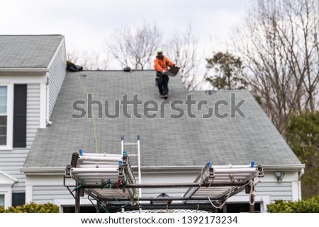 House during day over garage with truck, gray color Single Family Home and man walking on roof shingles and ladder during repair