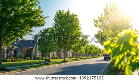 View of modern residential houses neighborhood street in Bentonville, Northwest Arkansas, sunny flare day, fast growing city lifestyle Royalty-Free Stock Photo #1392175103