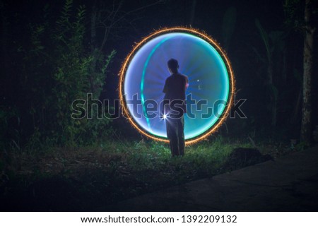 someone's silhouettes on a green and blue circle created with light painting 