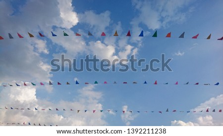 Triangle multi color flag with clouds and blue sky.