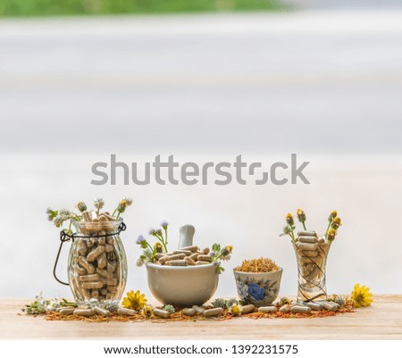 Herbal  alternative  medicine  capsules  from  various  herb  in  glass  bottle  and  white  mortar  on  wood  table  with  nature  blurry  background  for  good  health