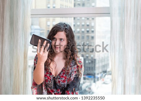 Closeup of young happy woman girl sitting at window in home room looking at phone smiling in NYC taking selfie