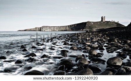 Dunstanburgh Castle and stones at Sunset