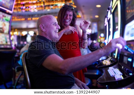 elderly couple gambling on slot machine in casino Royalty-Free Stock Photo #1392244907