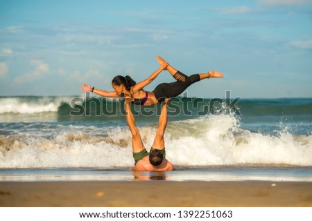 outdoors lifestyle portrait young attractive and concentrated couple of yoga acrobats practicing acroyoga balance and meditation exercise on beautiful beach in mind and body teamwork control